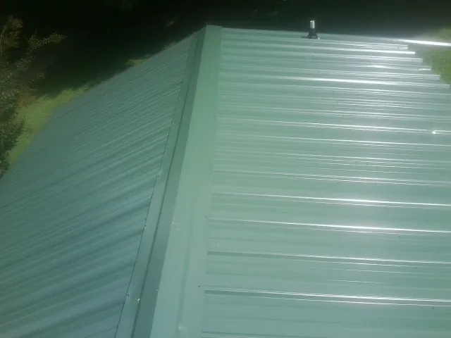 New green metal panels meeting at the ridge of a roof — Flat Roof Repair work by our crew in Golf