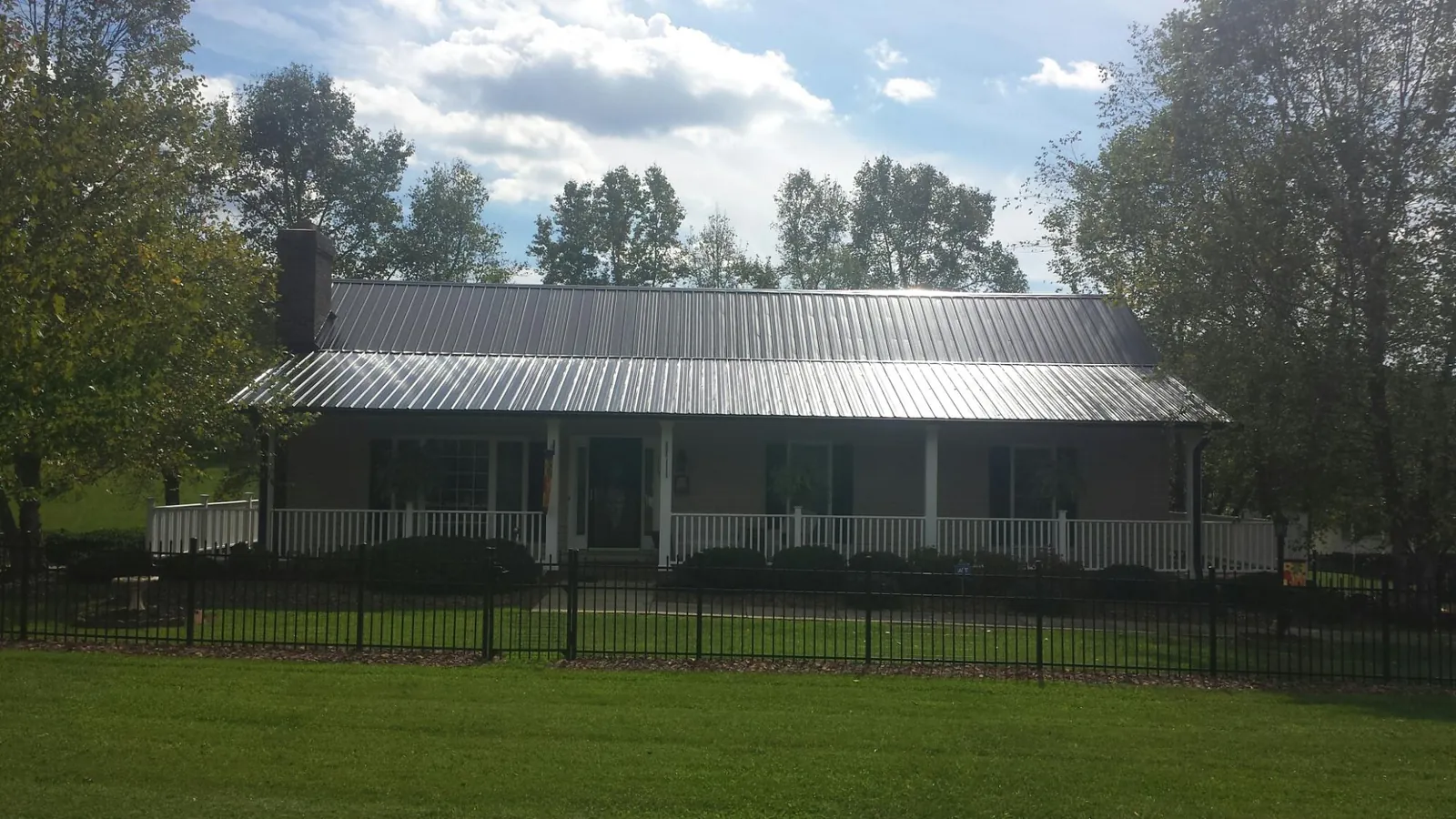 Gray metal roof on a brick ranch with a full width front porch — Gutter Guard Installation work by our crew in Golf